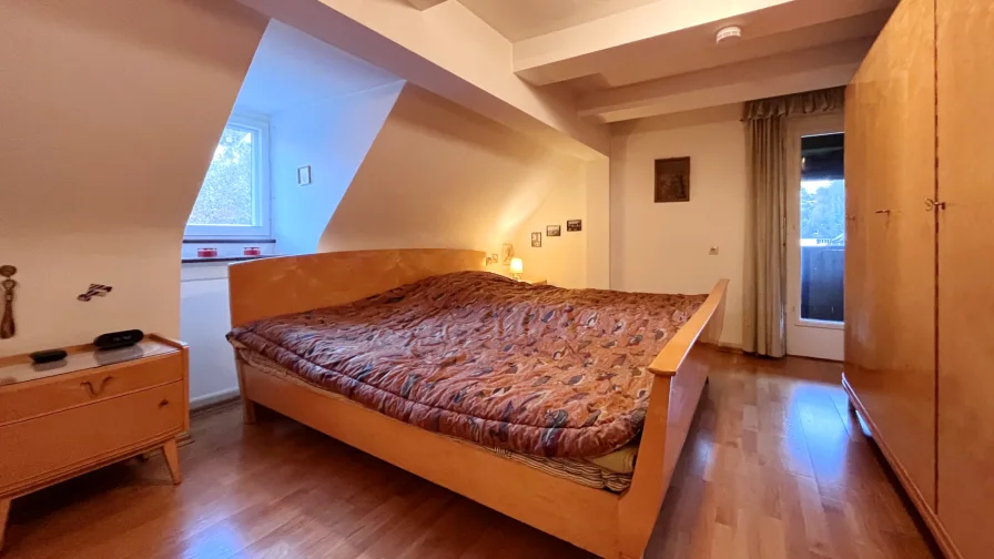 Schlafzimmer mit gemütlichen Dachschrägen und Zugang zum Balkon