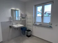 Einblick in das Pflegebad mit WC, Dusche und Waschtisch