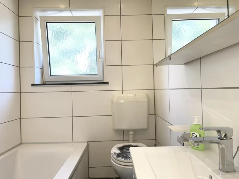 Badezimmer mit Fenster, Wanne, Waschbecken und WC