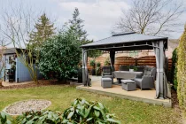 Gemütlicher Gartenbereich mit überdachtem Freisitz, Grillplatz und Platz für ein Jacuzzi mit Stromanschlüssen.