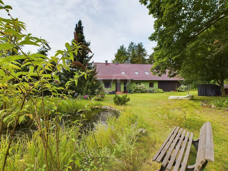 Grundstücksansicht mit Teich und Immobilie