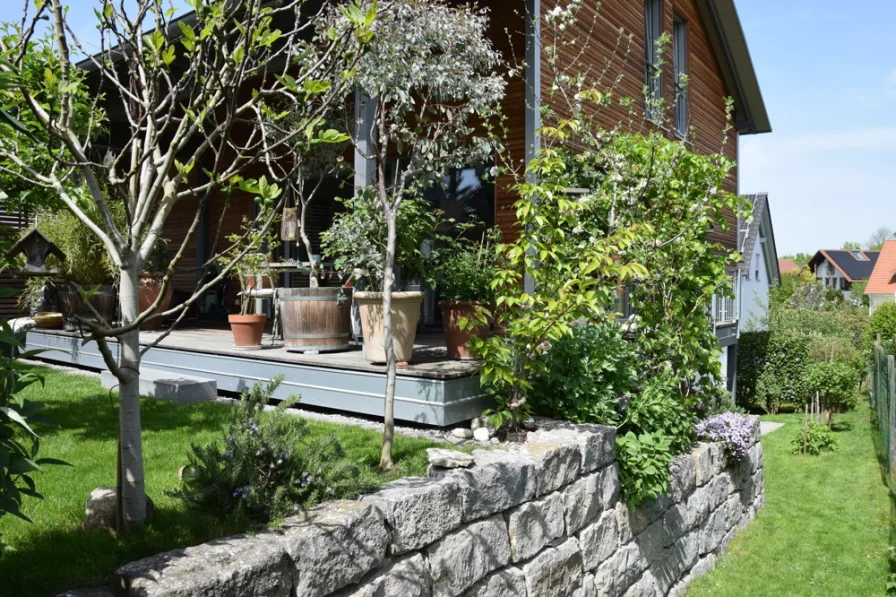 Teil des Gartens mit Natursteinmauer und überdachter Terrasse