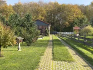 Grün- und Gartenflächen mit Blick zur großen Garage und Zufahrt!