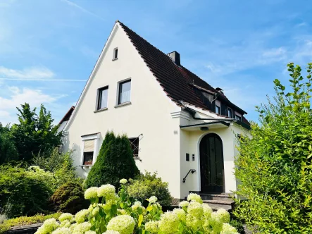 Ostansicht mit Hauseingang und Vorgarten - Haus kaufen in Ebern - Gepflegtes Ein- bis Zweifam.-Wohnhaus mit Garage und hübschem Garten, viel Platz: 7 Zimmer, Küche, 2 Bäder/WC, Grund 628m²