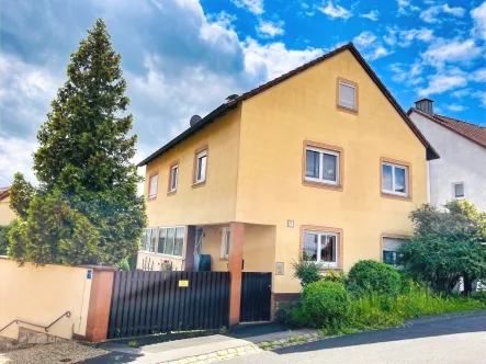 Ansicht des Hauses mit Hoftoranlage/Zugang - Haus kaufen in Sulzfeld - *PREISREDUZIERUNG* Wintergarten inklusive... Haus mit Garten und Nebengebäude in zentraler Lage mit unverbauter Aussicht!