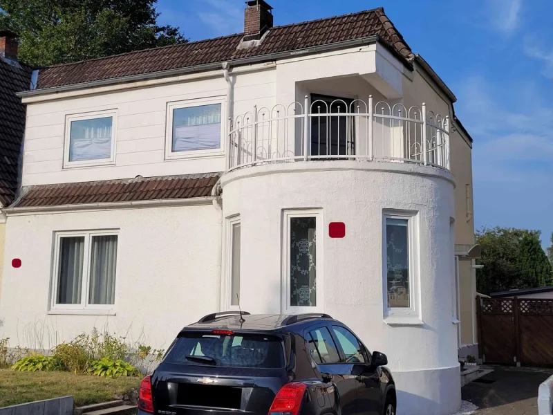 Hausfront mit Balkon und zwei Stellplätzen - Haus kaufen in Neumünster / Gadeland - Charmante, modernisierte DHH in Gadeland mit Balkon, zwei Stellplätzen und schönem Garten