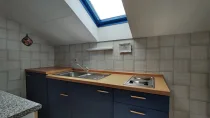 Die Küche mit 2 Küchenzeilen, einer Kochgelegenheit, einem Spülbecken und einem Dachfenster