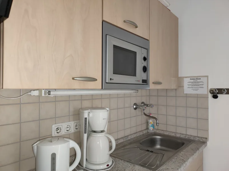 Die kleine Küchenniesche, ausgestattet mit einer Mikrowelle und einem Kühlschrank