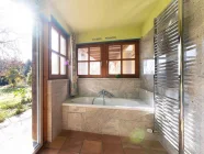 Die weitere Ansicht auf das Badezimmer mit Badewanne und Waldblick