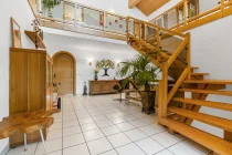 Der Eingangsbereich mit Massivholztreppe, Galerie und Giebelverglasung bildet das Herzstück des Hauses