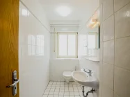 Eines der separaten WCs mit Waschbecken und Fenster