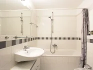 Modernisiertes, hell gefliestes Badezimmer...