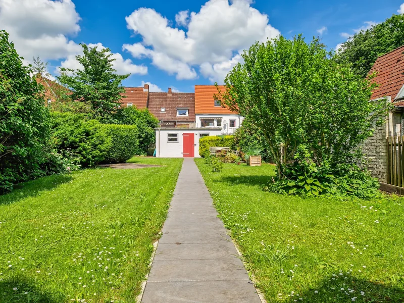 Blick in den Garten mit Terrassenflächen und Fahrradschuppen