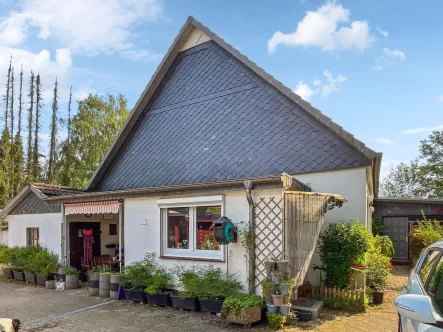 Giebelseite, rechts Zugang zur Hauptwohnung, unter kleinem Vordach Eingang zur Einliegerwohnung, in der Mitte gedeckter Freisitz der Einliegerwohnung - Haus kaufen in Achim - Viel Wohnraum, großer Garten und viele Möglichkeiten!