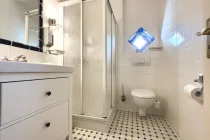Hell gefliestes Gäste-WC mit Dusche im Erdgeschoss