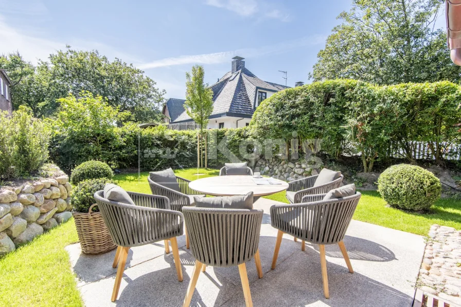 sonnige Südterrasse mit Strandkorb und Gartenmöbeln, sowie Blick in den pflegeleichten Gartenbereich