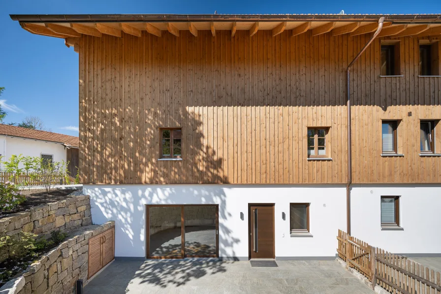 Ostansicht, die zweite Eingangstüre, Terrasse und holzverkleidete Fassade aus Fichtenholz 