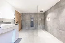 Die bodengleiche Dusche und Badewanne präsentieren sich mit Armaturen von Hansgrohe und Axor