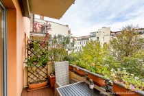 Balkon mit elektrischer Markise und Blick in den sonnigen Innenhof 