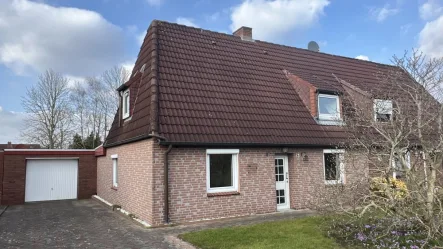 Hausansicht mit Garage - Haus kaufen in Sande - Doppelhaushälfte mit Potenzial nahe Jadebusen